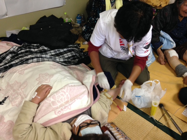 미나미-아소 내 하쿠수이 체육관에 마련된 대피소. 국경없는의사회 간호사 토모유키 하타이가 정맥 주사를 준비하고 있다. © Shumpei Tachi/MSF