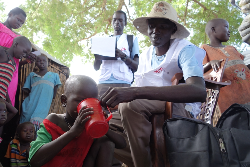 국경없는의사회 지역사회보건팀의 파울리노가 말라리아 백신 치료제를 제공한 아동이 입을 헹구도록 돕고있다. ⓒJacob Kuehn/MSF