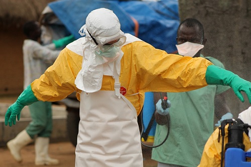 라이베리아의 포야 에볼라 관리센터에서 프랑스 위생학자 제롬 기요모가 착용복을 벗으면서 염소수로 소독을 받고 있다. ©MSF